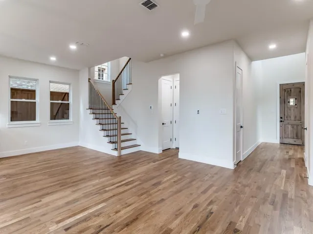 a view of an empty room with wooden floor and windows