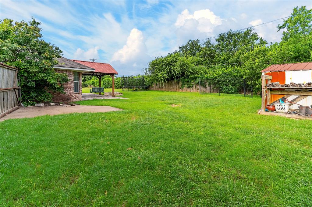 124 Topaz Circle Hewitt, TX 76643 - Photo 31 of 35 Expansive green lawn with a covered patio featuring a red metal roof and wood supports