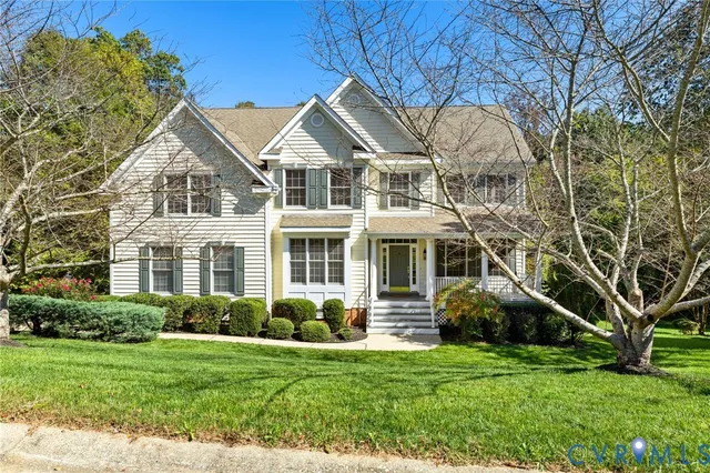 a view of a white house next to a yard with big trees