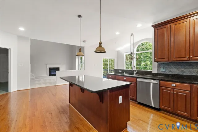 a kitchen with stainless steel appliances granite countertop a sink a stove and a wooden floor