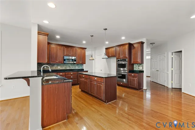 a kitchen with stainless steel appliances granite countertop a stove top oven a sink dishwasher a refrigerator and a microwave