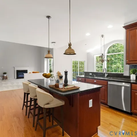 a kitchen with stainless steel appliances granite countertop a sink a stove a kitchen island with chairs and cabinets