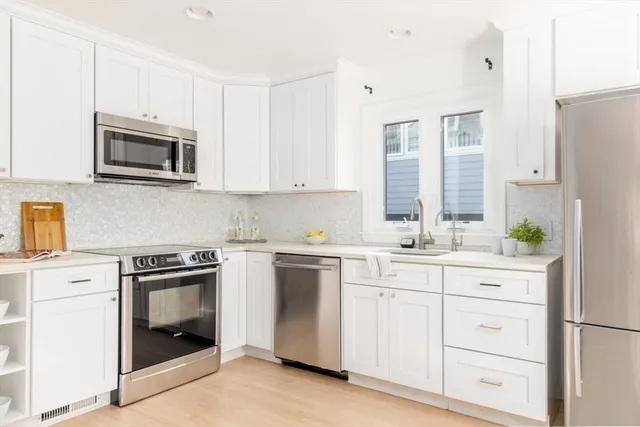 a kitchen with stainless steel appliances granite countertop white cabinets and a stove
