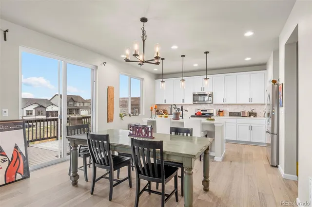 a kitchen with stainless steel appliances kitchen island granite countertop a dining table chairs and white cabinets