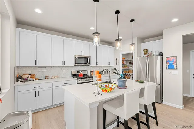 a kitchen that has a lot of cabinets a sink and appliances