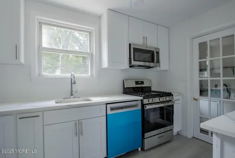a kitchen with cabinets stainless steel appliances a sink and a window