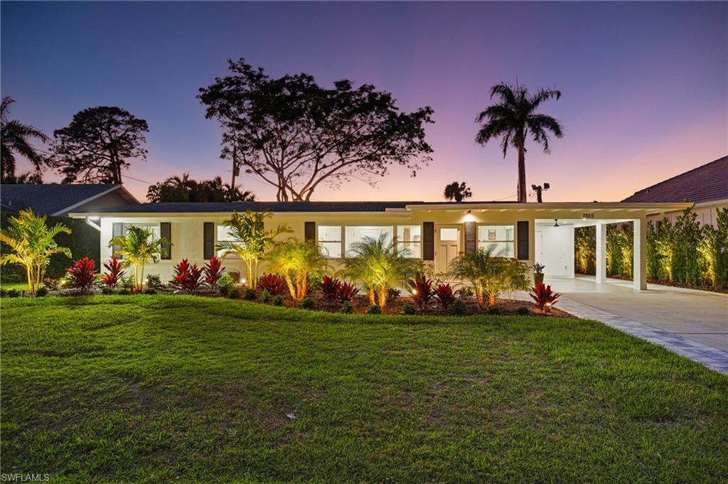 a view of a house with a big yard and palm trees
