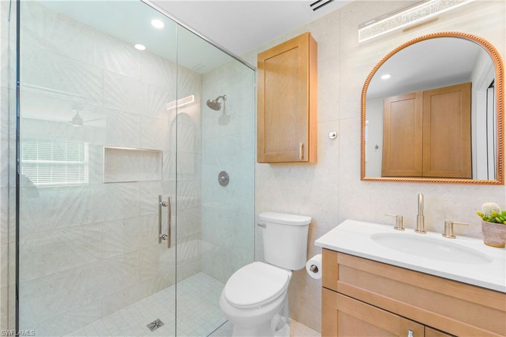 2855 10th Street North Naples, FL 34103 - Photo 21 of 29 a bathroom with a granite countertop sink a toilet and shower