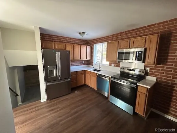 a kitchen with granite countertop a refrigerator stove top oven and sink