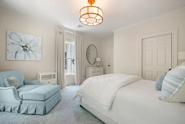 a bedroom with a bed a chandelier and a mirror