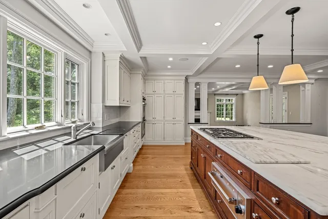 a large kitchen with kitchen island a large counter space a large window and stainless steel appliances