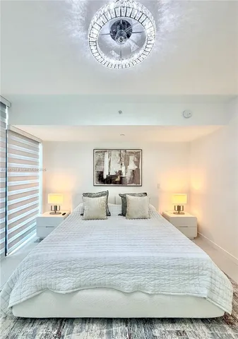 a bedroom with a large bed and a chandelier