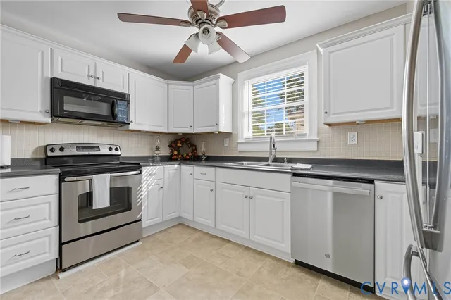 a kitchen with stainless steel appliances granite countertop white cabinets a window and a sink