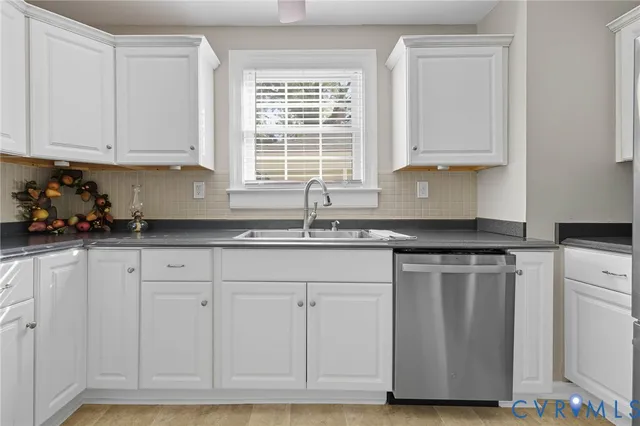 a kitchen with white cabinets and sink