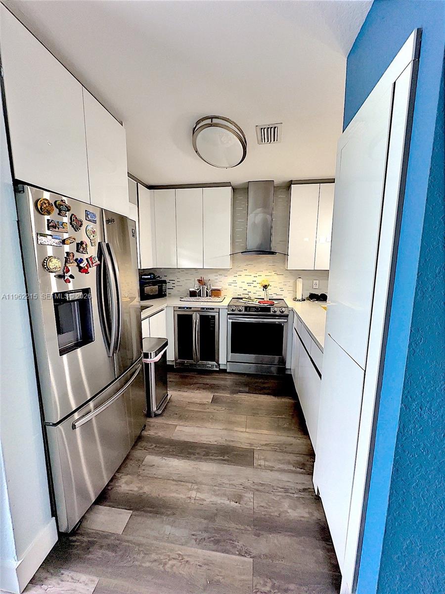6761 Northwest 182nd Street, Unit 103 Hialeah, FL 33015 - Photo 4 of 13 a kitchen with white cabinets and stainless steel appliances