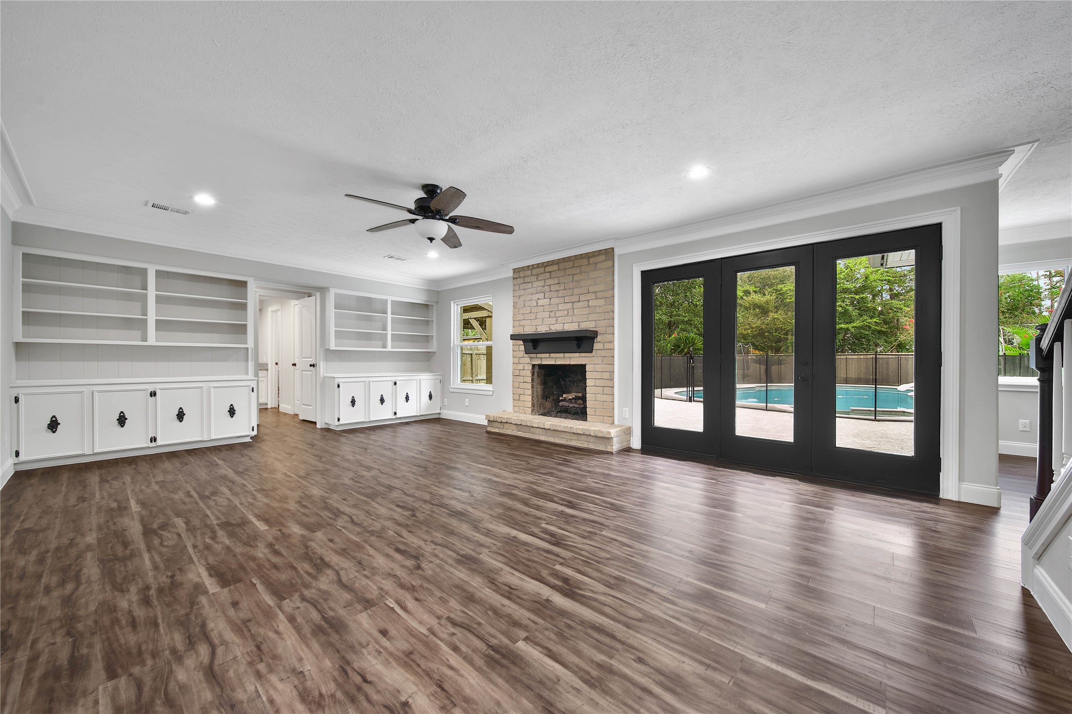 6407 Craigway Road Spring, TX 77389 - Photo 4 of 47 Spacious family room features built-in storage and display shelving plus a gas log fireplace. Beautiful triple French doors fill the room with natural light while offering unobstructed views of the patio, backyard, and pool.