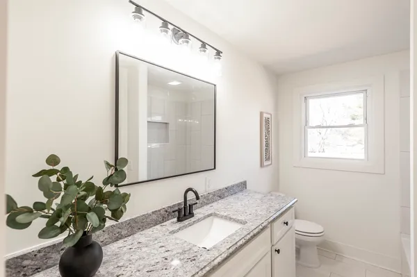 a bathroom with a granite countertop sink and a mirror