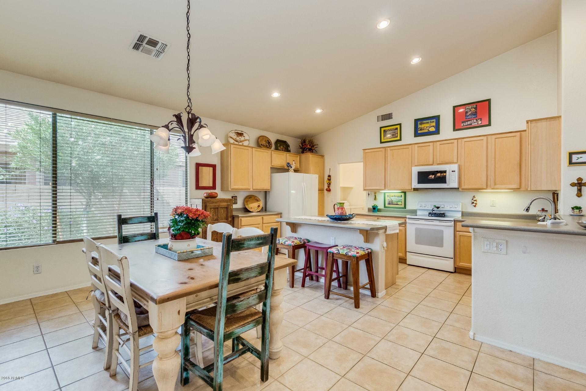 1141 East Ranch Court Gilbert, AZ 85296 - Photo 3 of 22 a open dining room with stainless steel appliances kitchen island granite countertop a table chairs and a view of living room