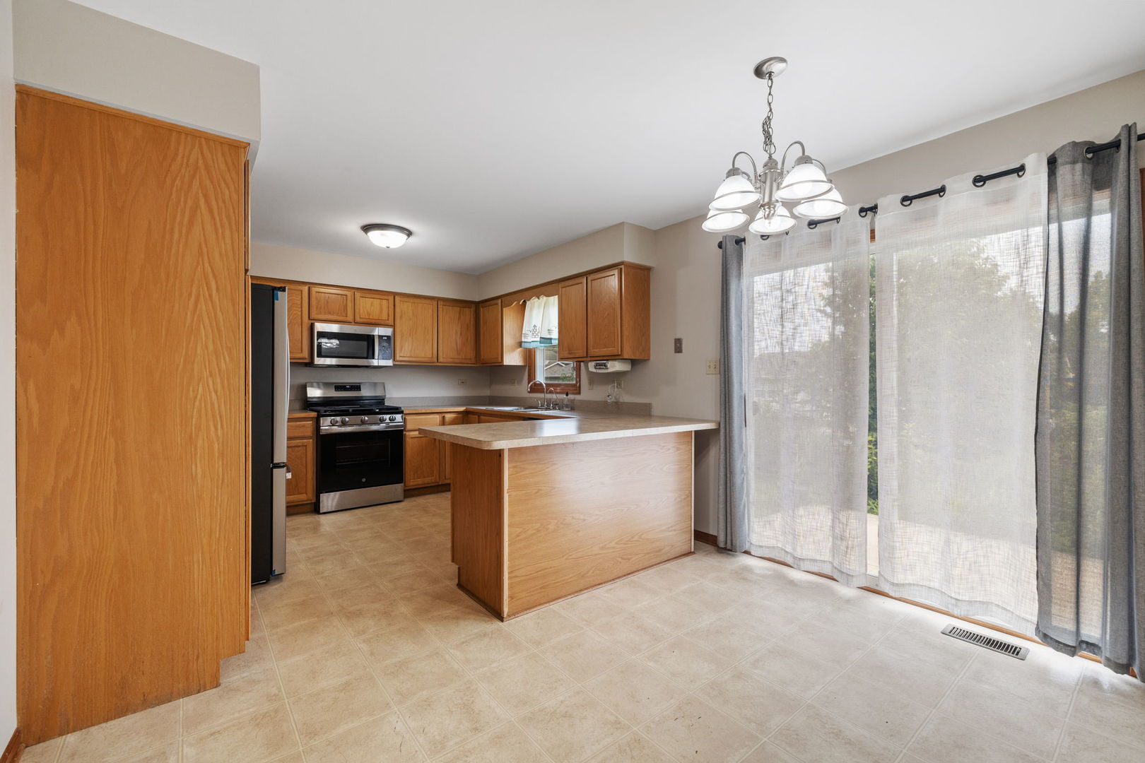 2714 Billie Limacher Lane Plainfield, IL 60586 - Photo 7 of 26 a large kitchen with a refrigerator a sink dishwasher a stove and a dining table with wooden floor