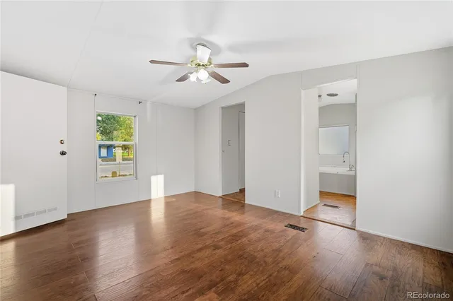 an empty room with wooden floor chandelier fan and windows