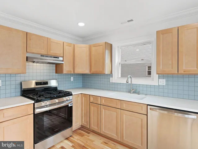 a kitchen with granite countertop a sink cabinets and stainless steel appliances