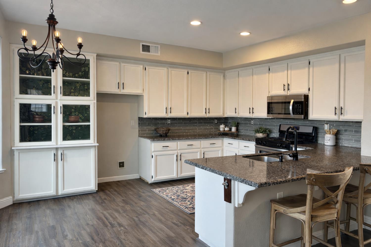 4909 Hidden Meadow Way Antelope, CA 95843 - Photo 11 of 35 a kitchen with stainless steel appliances granite countertop a stove a sink a microwave and white cabinets