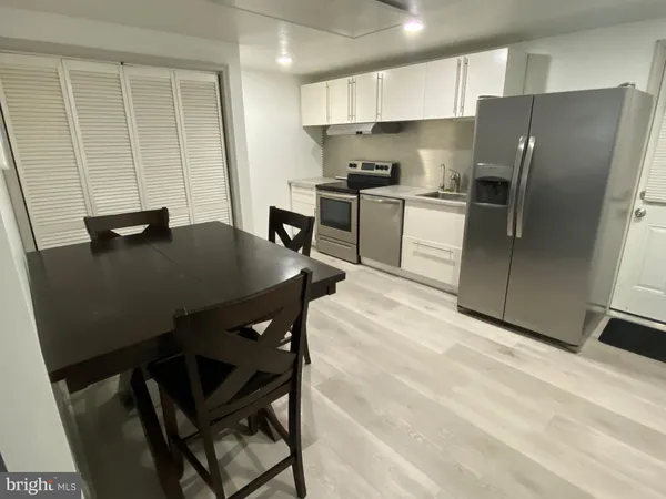 a kitchen with stainless steel appliances a table chairs and a refrigerator
