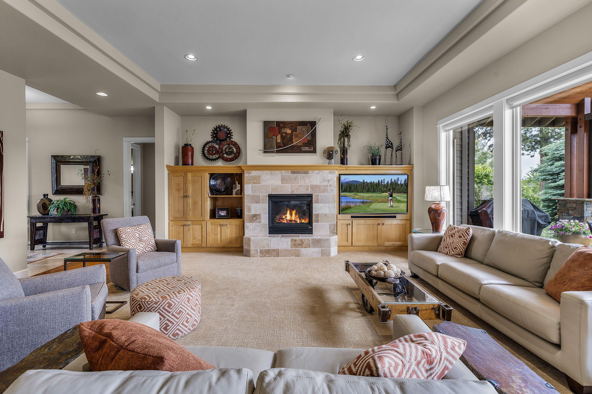 Elegant tray ceilings and custom alder cabinetry flank the stone encased gas fireplace.