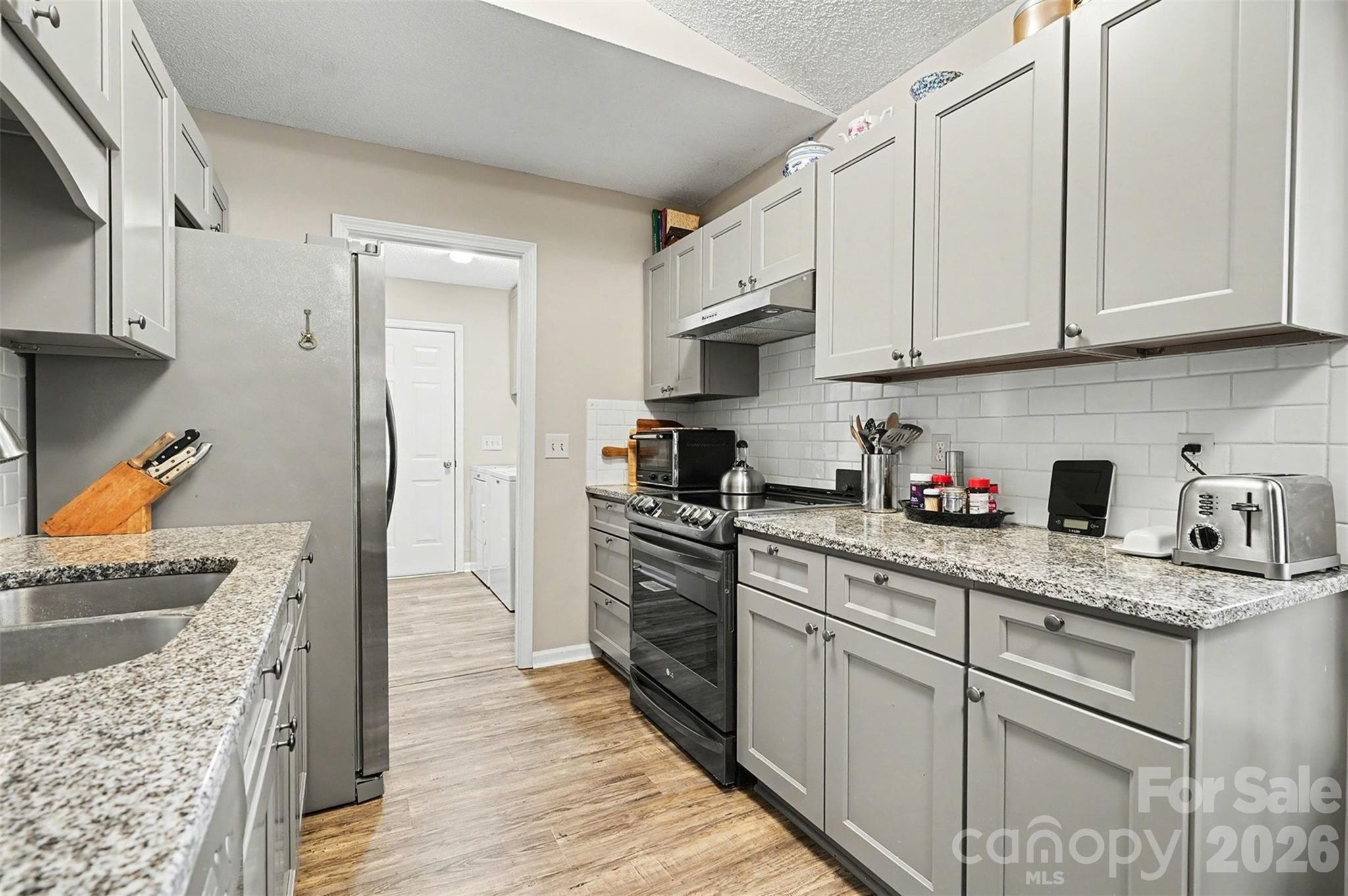 228 Creek View Road Mooresville, NC 28117 - Photo 12 of 40 a kitchen with stainless steel appliances granite countertop a stove a sink dishwasher and a refrigerator with wooden cabinets