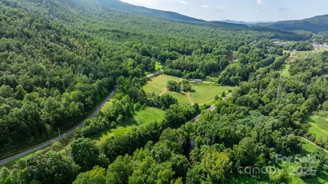 an aerial view of residential house with outdoor space and trees all around