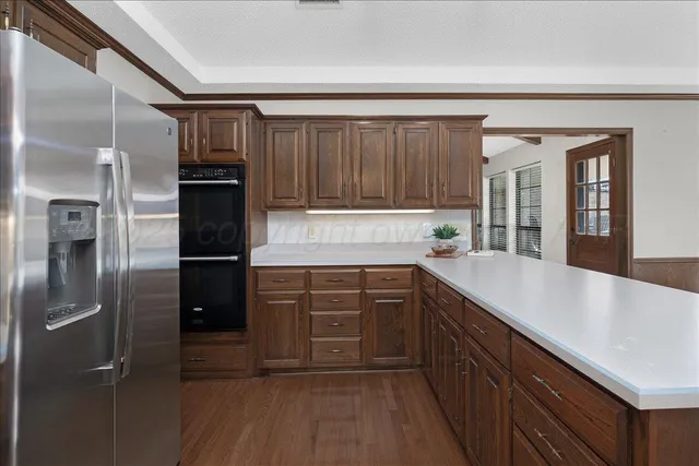 a kitchen with kitchen island granite countertop a refrigerator and a sink