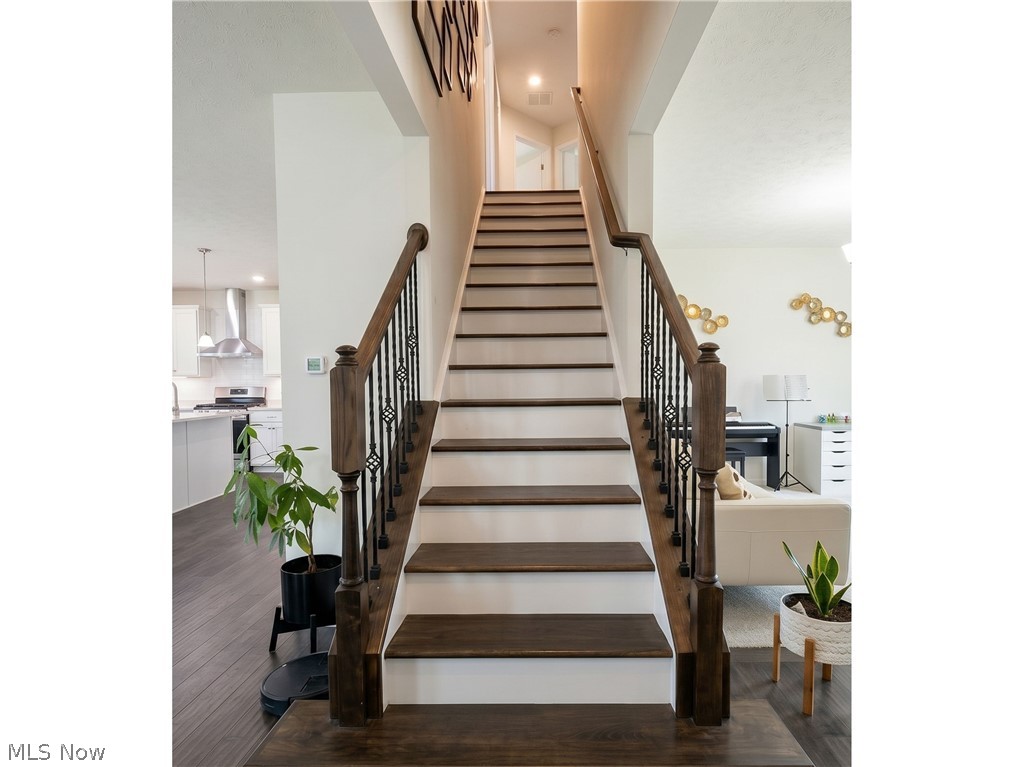 4509 Millbrook Way Akron, OH 44321 - Photo 15 of 27 Staircase featuring dark wood-finish treads and handrails, white risers, and wrought iron balusters