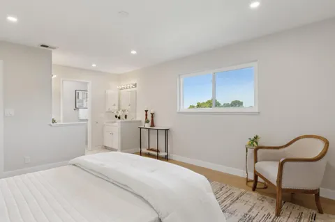 a bedroom with a bed a chair and potted plant