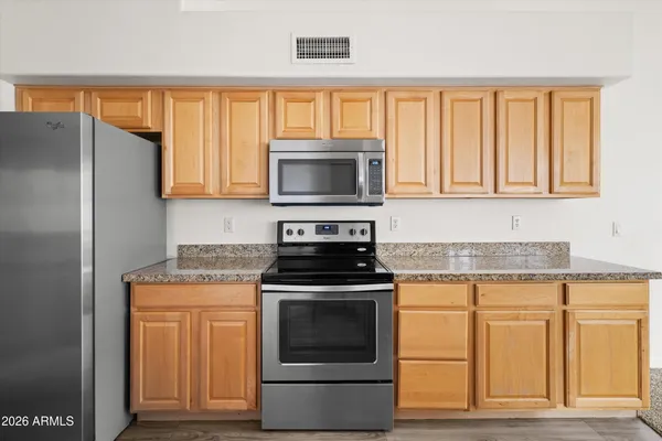 a kitchen with granite countertop a stove top oven cabinetry and a refrigerator