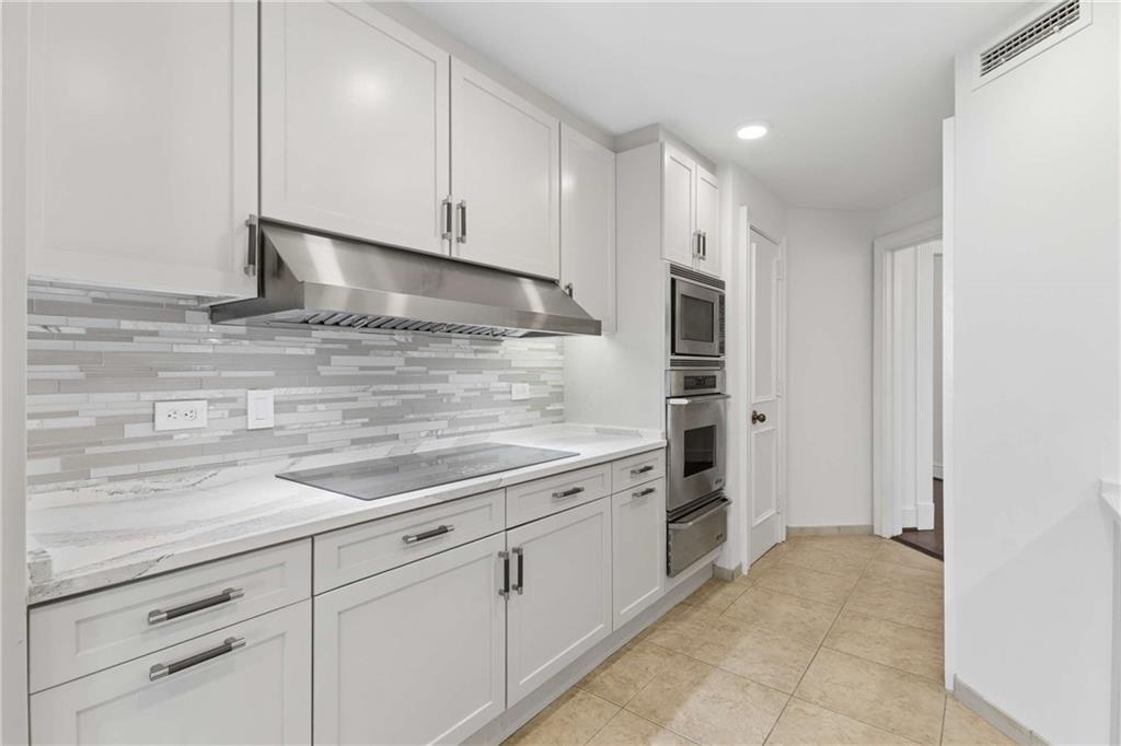 2660 Peachtree Road Northwest, Unit 13F Atlanta, GA 30305 - Photo 23 of 56 a kitchen with granite countertop white cabinets and white stainless steel appliances
