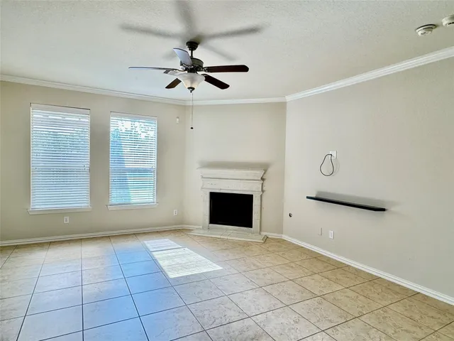 a view of an empty room with window and chandelier fan