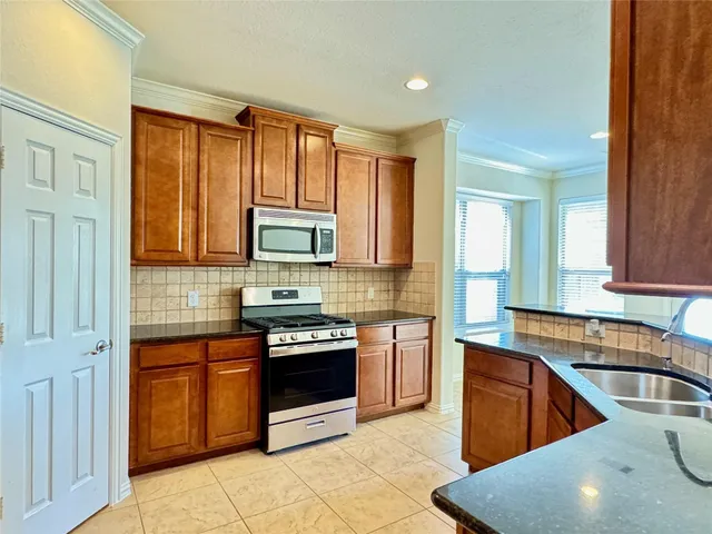 a kitchen with stainless steel appliances granite countertop a stove a sink and a microwave