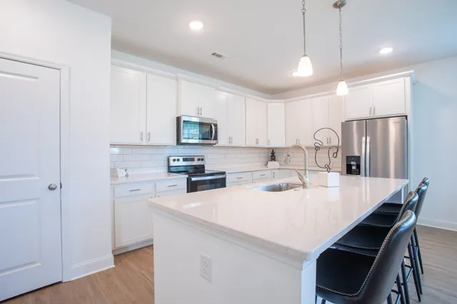 a kitchen with kitchen island a white counter top space stainless steel appliances cabinets and wooden floor