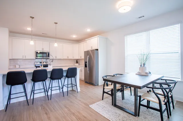 a kitchen with stainless steel appliances granite countertop a table chairs refrigerator sink and cabinets