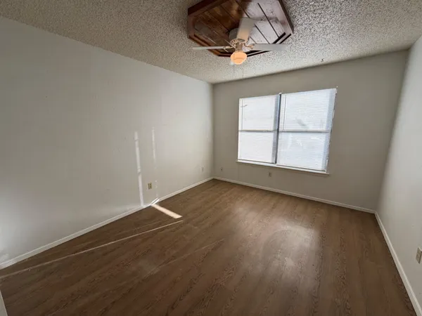 an empty room with wooden floor and windows