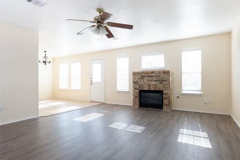 an empty room with windows fireplace and wooden floor