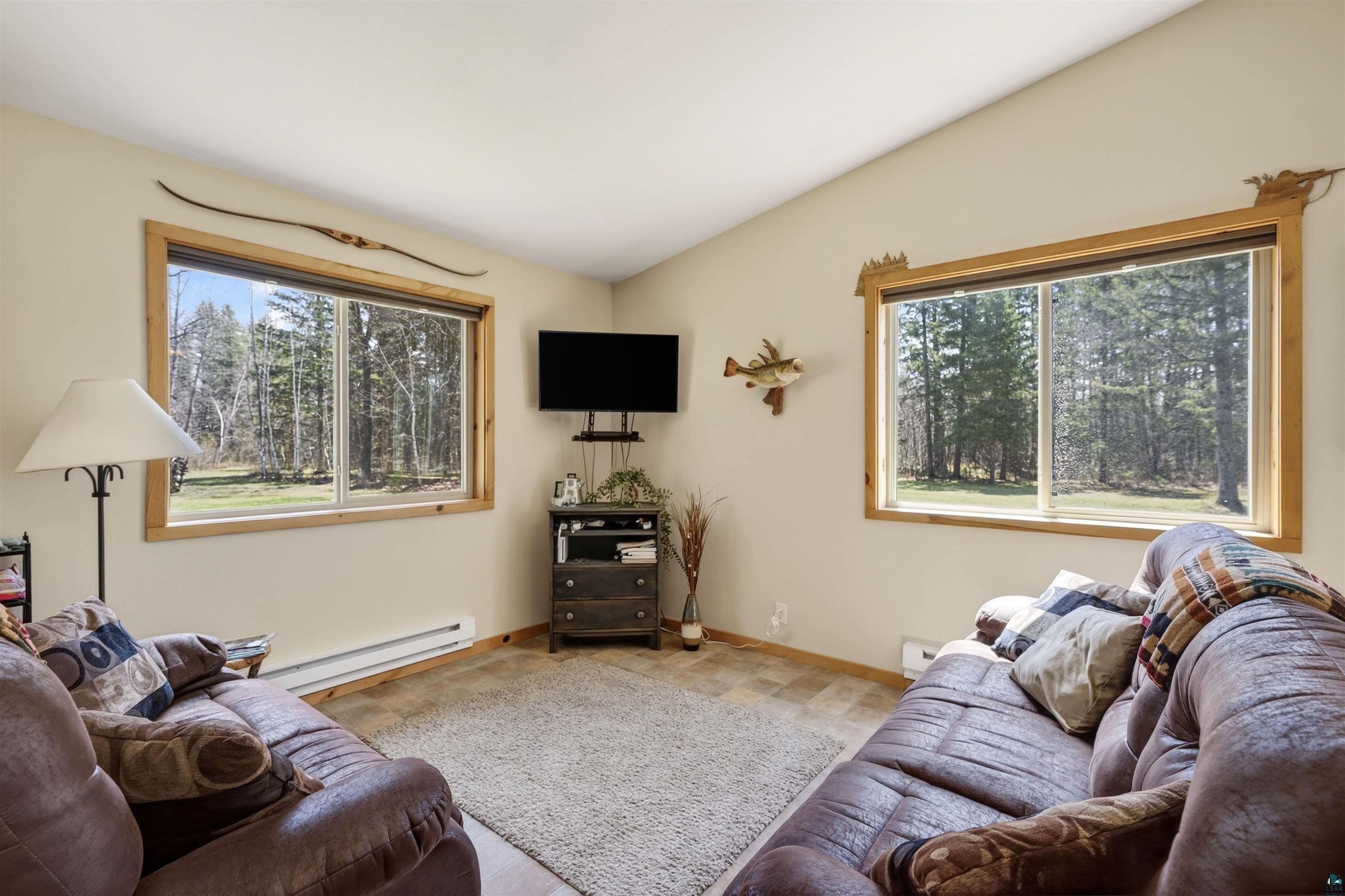 12235 East Crooked Lake Road Gordon, WI 54838 - Photo 10 of 48 Living area featuring two large windows, wood-finish window trim, and a wall-mounted television bracket