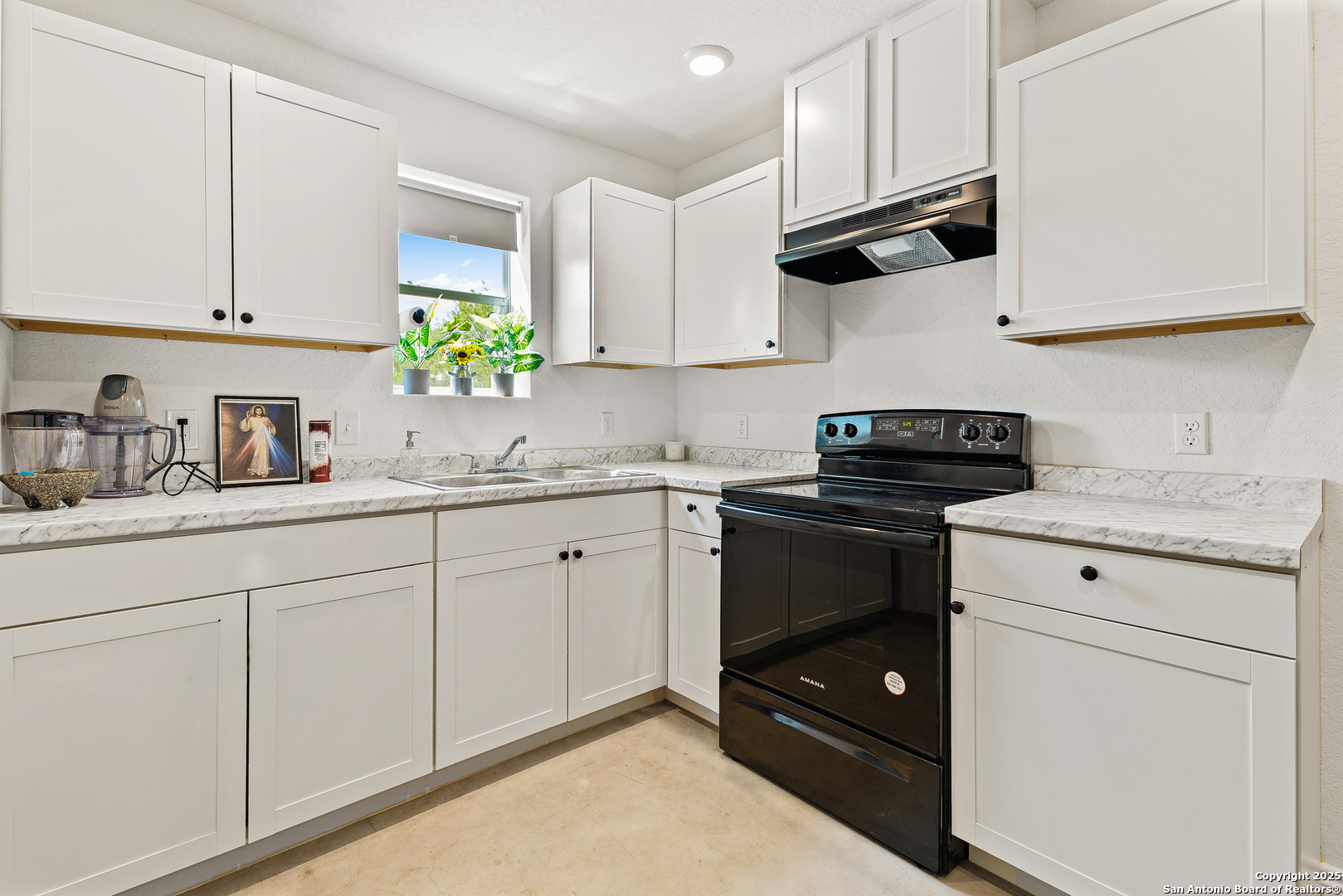 128 County Road 2672 Devine, TX 78016 - Photo 17 of 44 a kitchen with granite countertop white cabinets and black appliances