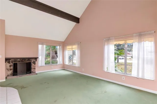 an empty room with windows and fireplace