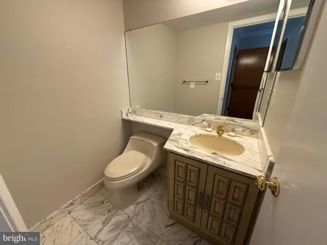 a bathroom with a granite countertop sink toilet and mirror