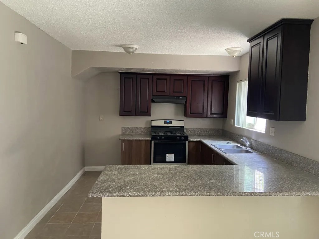 264 West Jackson Street Rialto, CA 92376 - Photo 4 of 32 a kitchen with granite countertop a sink a stove and a microwave oven