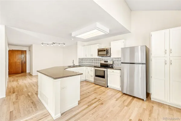 a kitchen with granite countertop a refrigerator stove top oven and sink