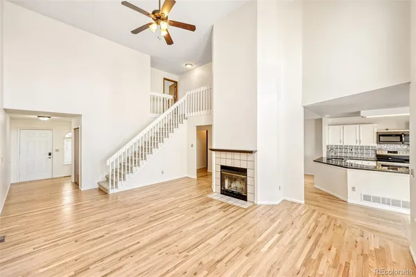a view of a kitchen and an empty room with wooden floor