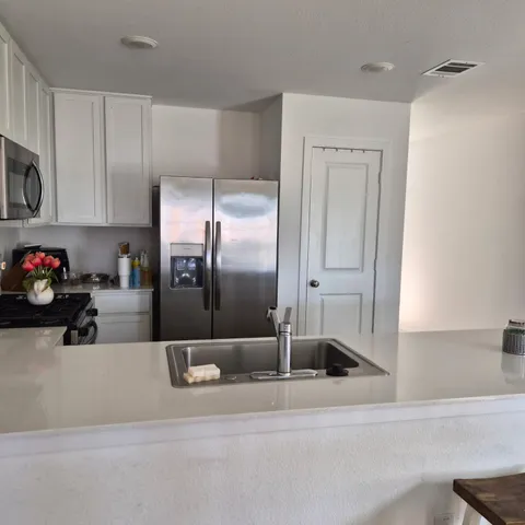 a kitchen with stainless steel appliances kitchen island granite countertop a refrigerator and a sink