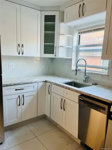 a kitchen with granite countertop a sink and a white cabinets